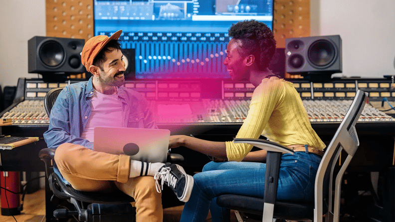 A man and woman smile warmly at each other in a music studio