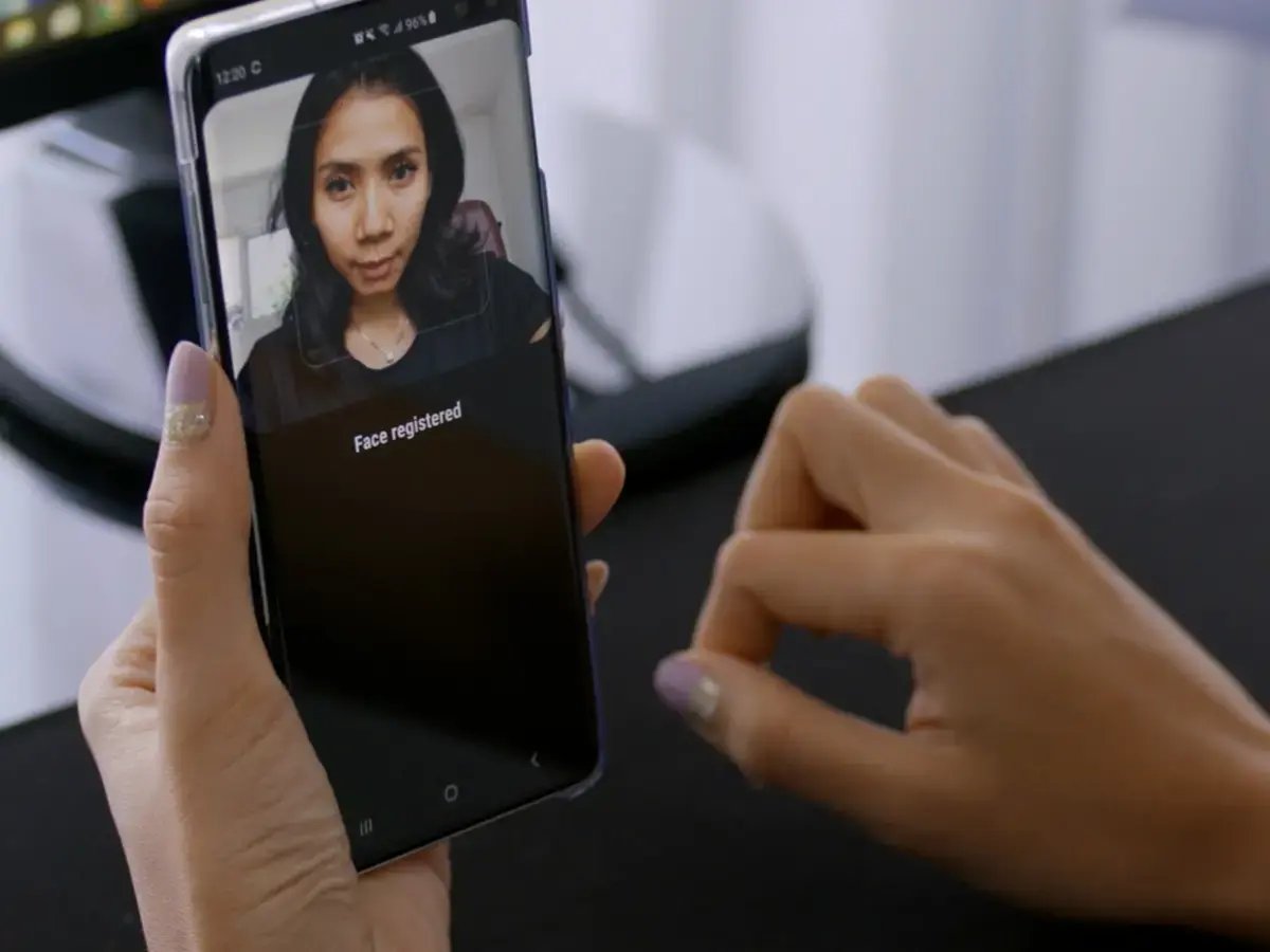 A person holds a smartphone with a screen showing a registered face