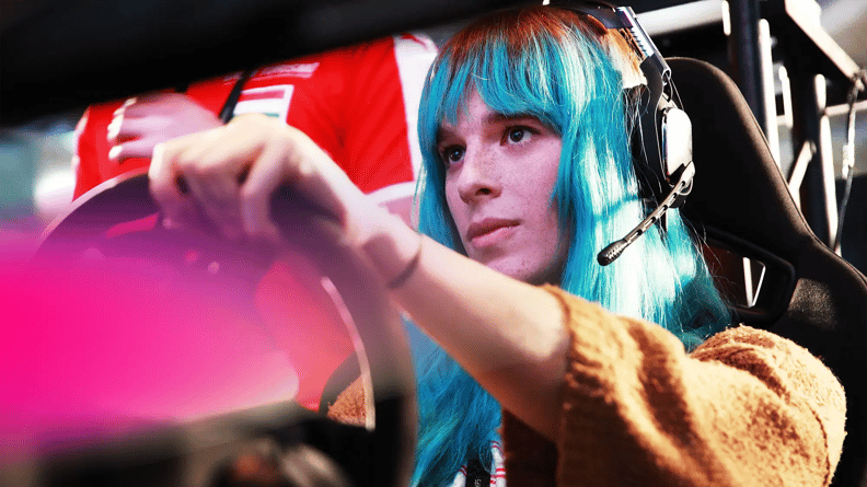 A person with long turquoise hair wears a headset, focused intently on steering a simulated racing game