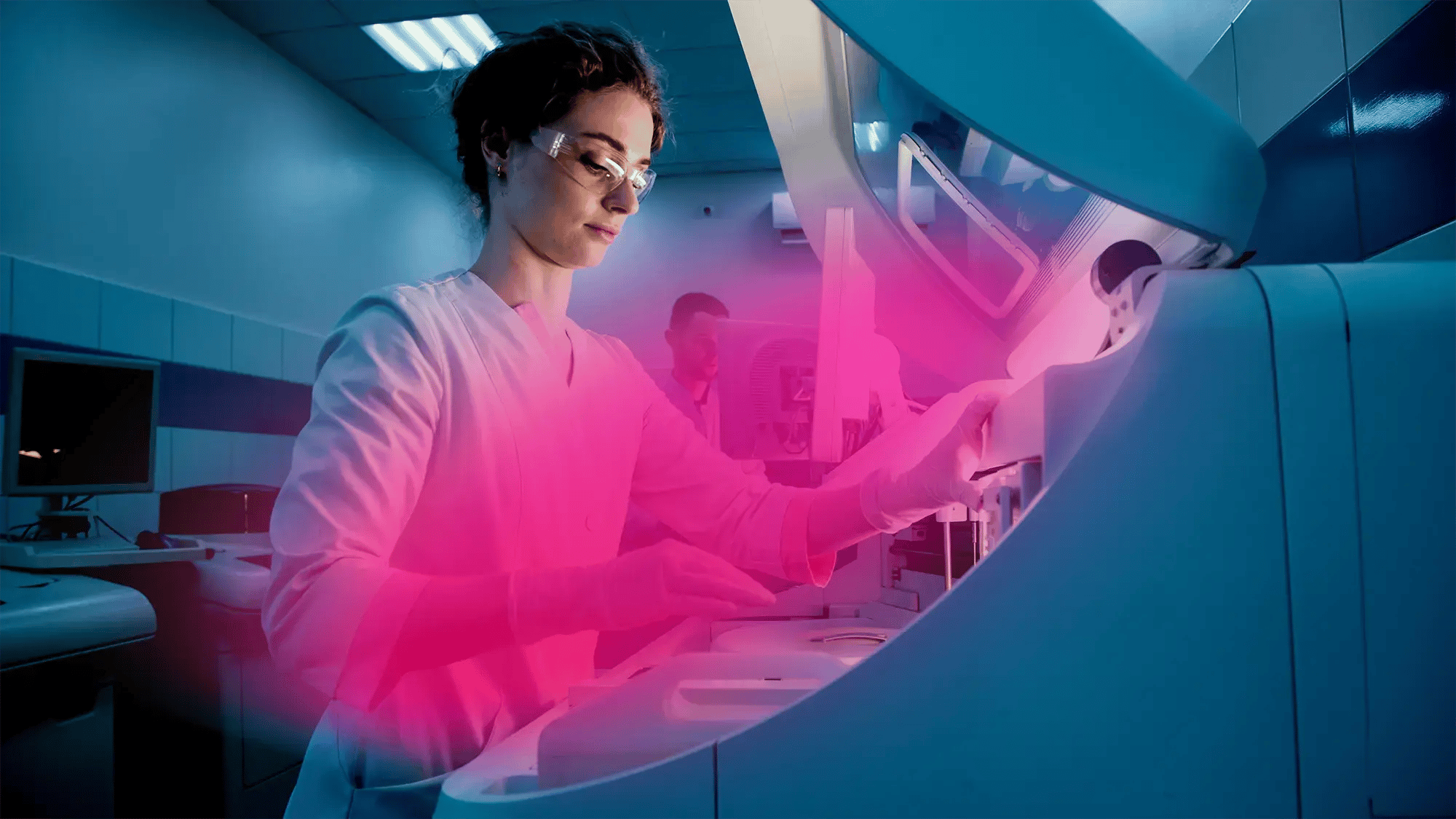 A scientist in a lab coat and safety goggles operates advanced lab equipment under blue lighting, focused and meticulous in a modern laboratory setting