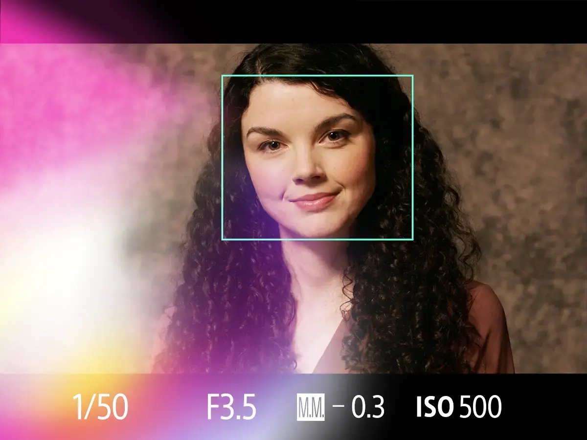 Close-up of a woman with curly hair and a gentle smile, framed by a cameras focus box