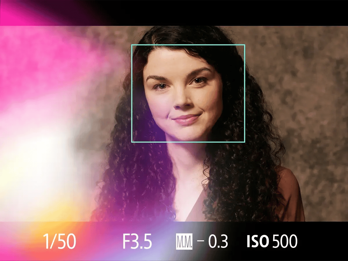 Curly-haired woman smiling gently, framed by a green rectangle against a textured brown backdrop
