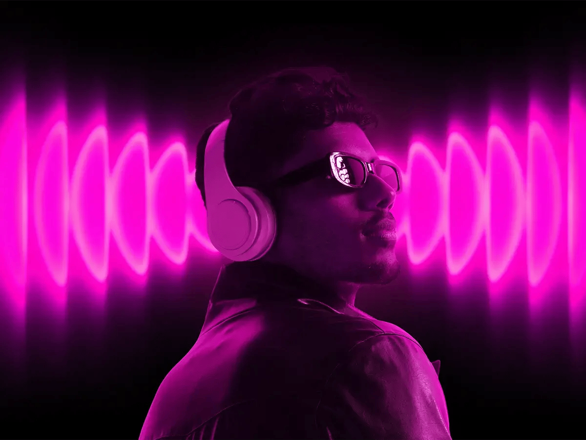Man wearing headphones and sunglasses, bathed in neon pink light