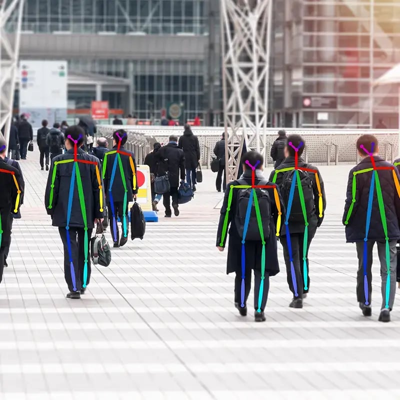 People walking in a city square, viewed from behind. Brightly colored lines and dots overlay the image like a motion tracking system