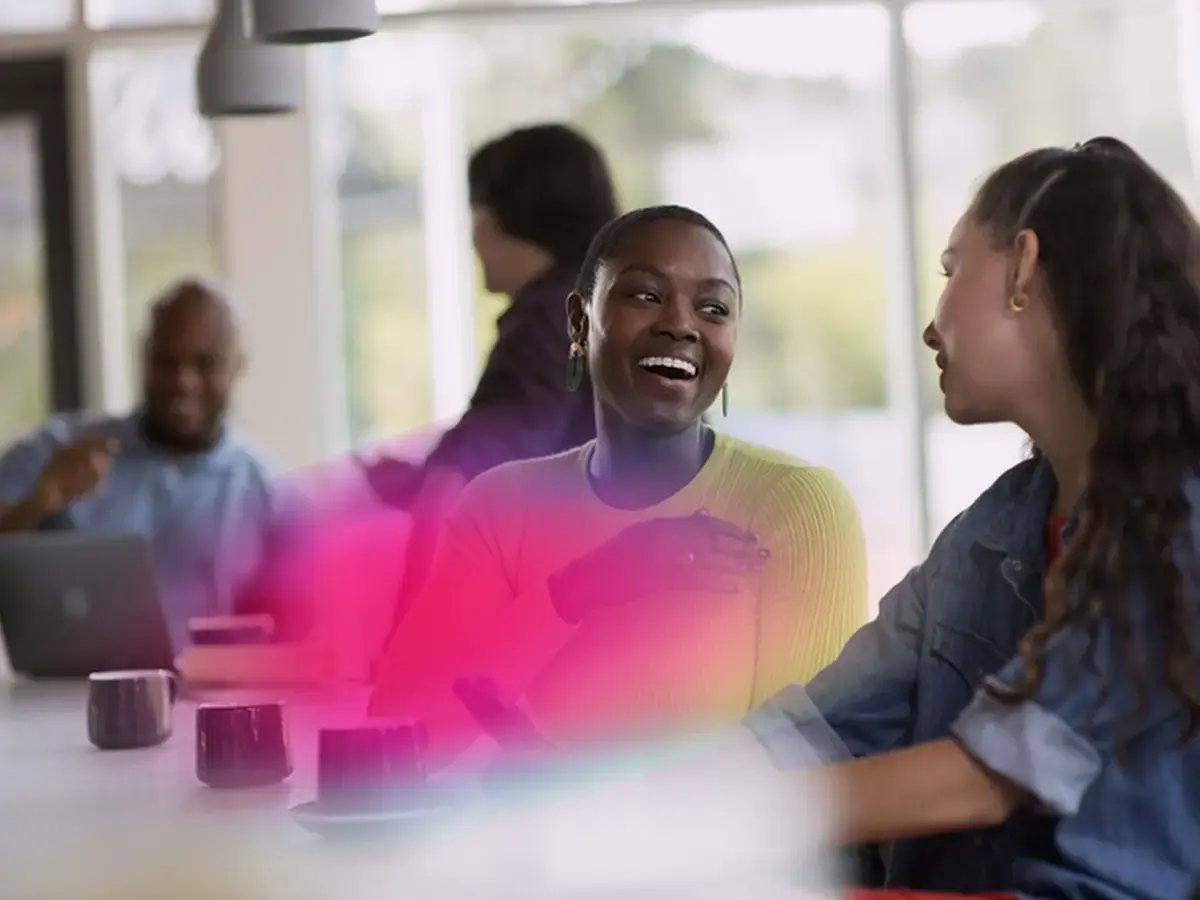 Two women smiling and chatting in a bright, modern café